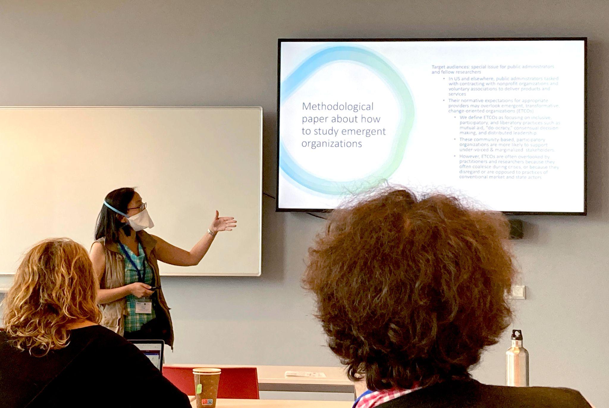 Katherine Chen presenting at the SASE 2022 annual meeting in Amsterdam while audience members look at her and her slides.