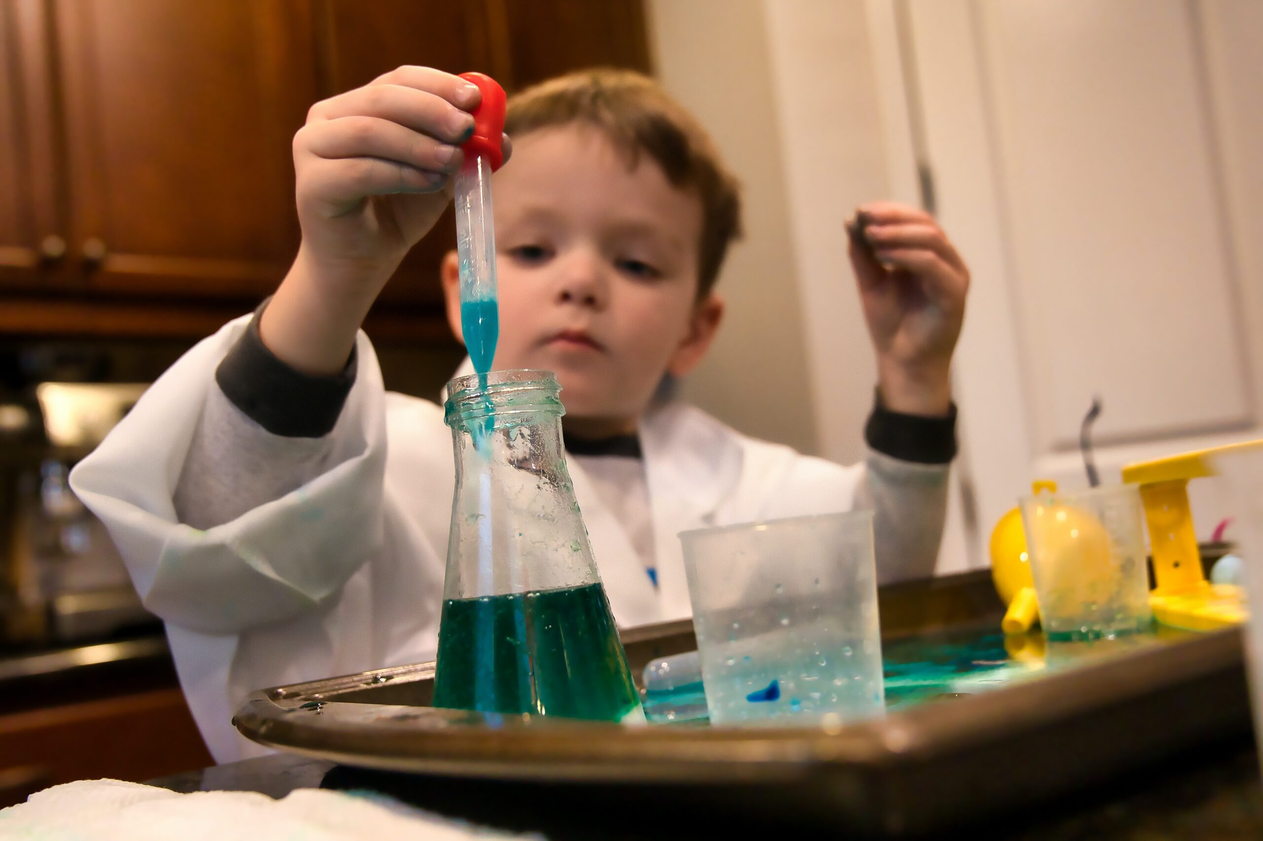 Boy in a long-sleeve white shirt conducting a science experiment.