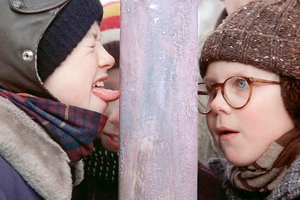 Boy with his tongue stuck on a frozen flagpole as another boy watches, stunned.