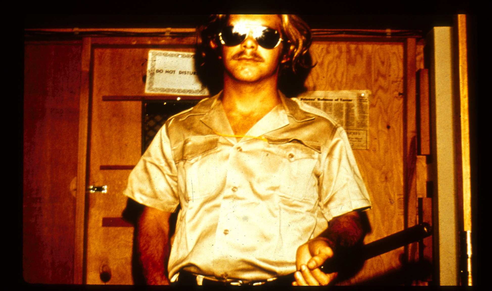 Guard with mirrored sunglasses holding a baton.