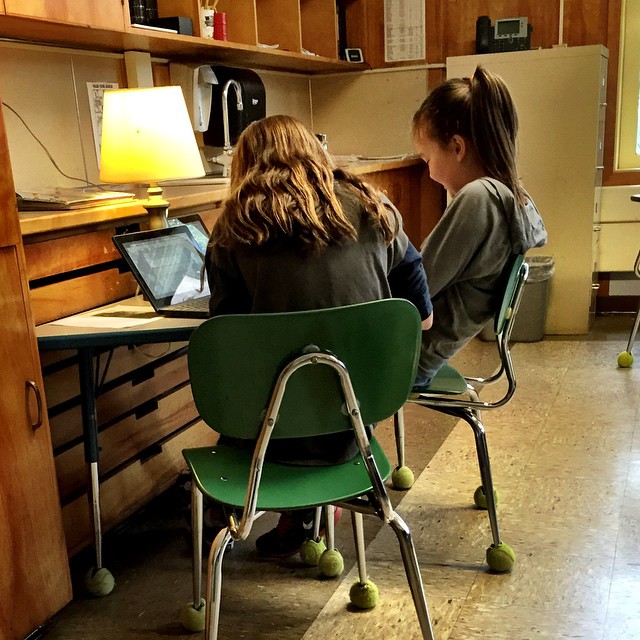 Two girls sitting in front of a laptop as part of a peer-editing process.