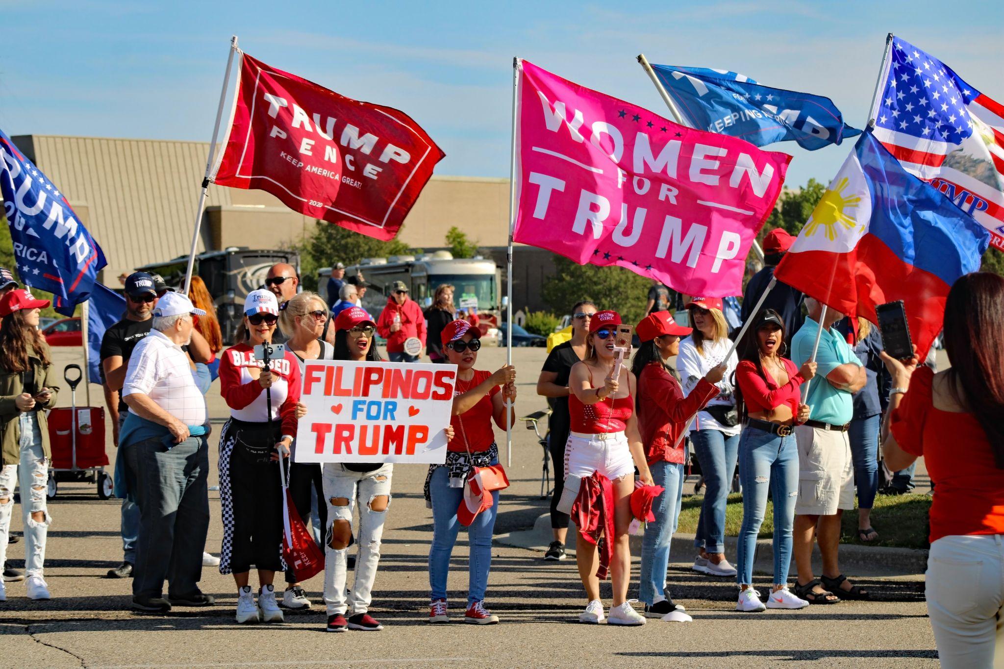 Crowd of people holding flags in support of Trump.