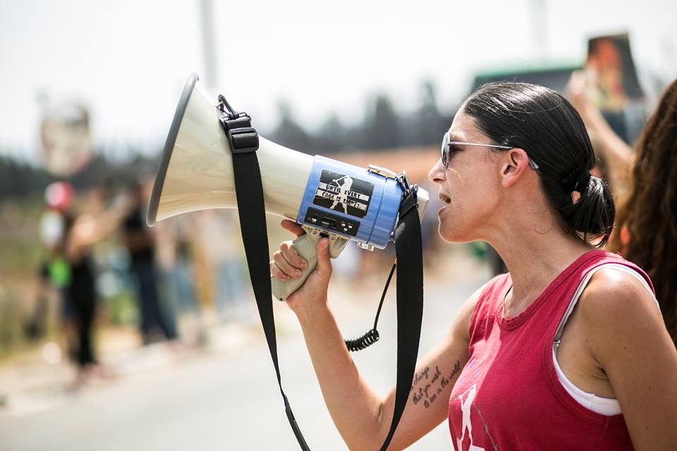 Activist speaking into a megaphone in front of a crowd of protesters.