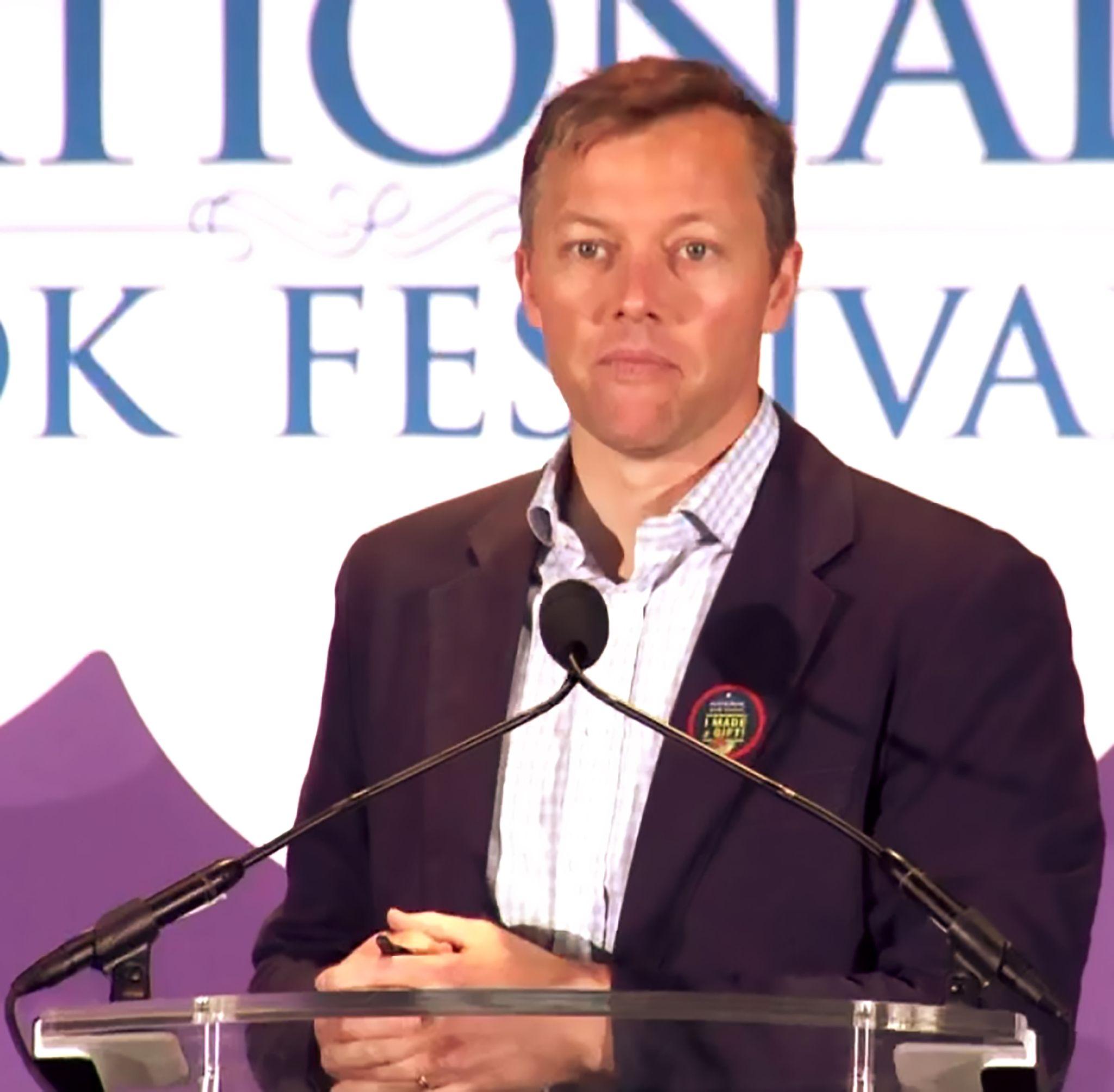Photo of Matthew Desmond in front of a lectern with two microphones.