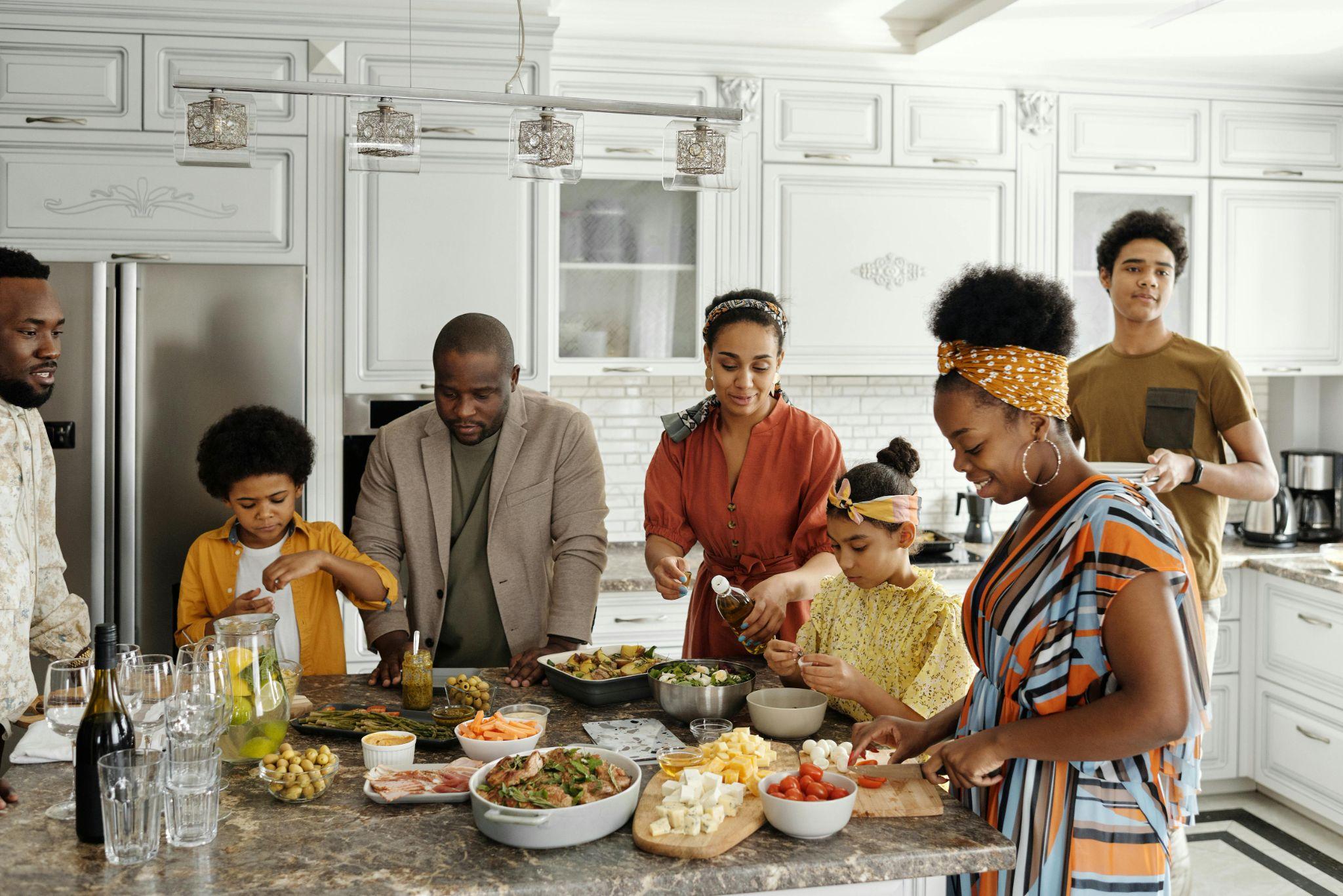 Photo of extended family standing around a kitchen island to serve themselves from an assortment of dishes.