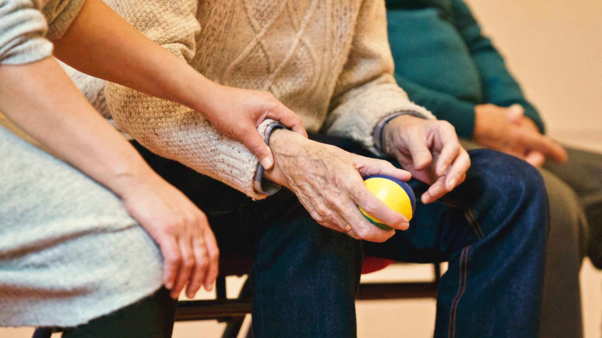 Woman holding the arm of an elderly man.