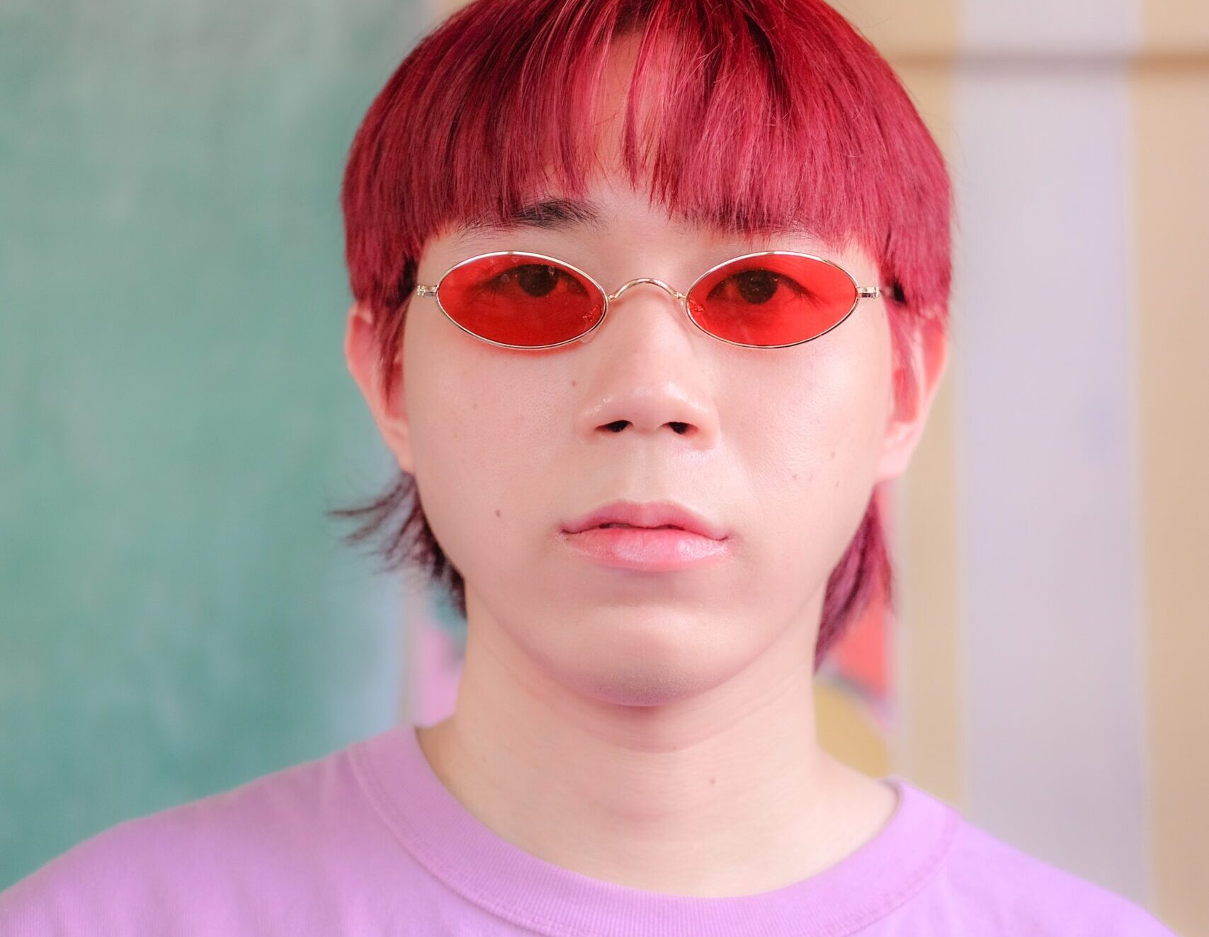 Man wearing red-tinted glasses and a pink shirt.