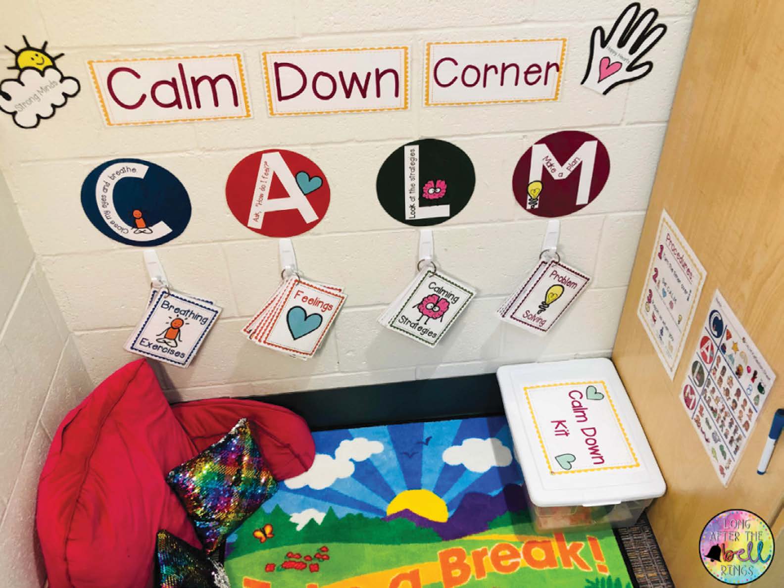 The corner of a classroom with the words calm down corner on the wall above. The corner has comfortable pillows, a colorful rug, a box labeled calm down kit, and laminated cards featuring breathing exercises, feelings, calming strategies, and problem solving approaches.