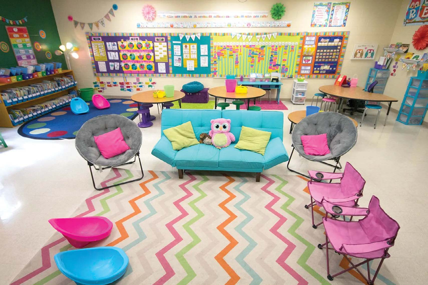 A primary classroom arranged with varied seating choices including cushioned chairs, folding chairs, and wobble seats around a colorful patterned rug.