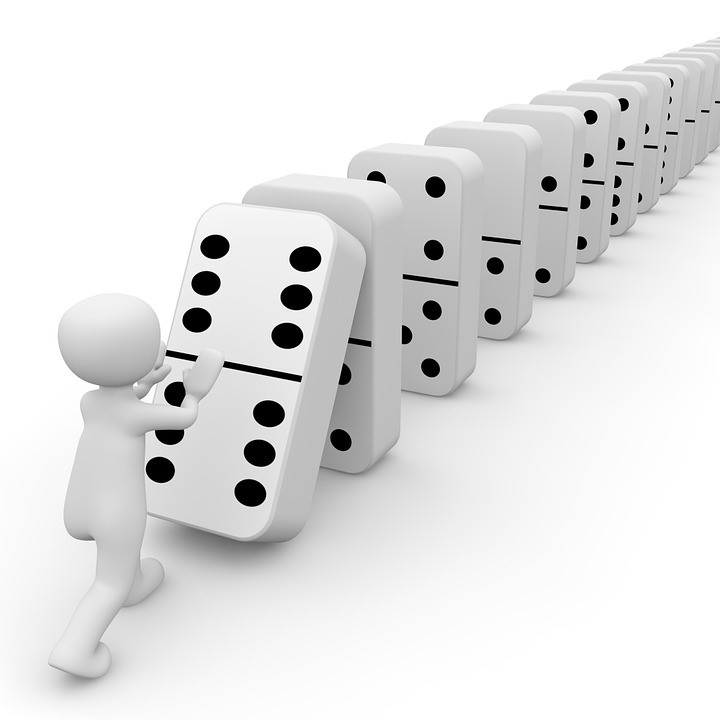 white 3-d cartoon knocking over a row of dominoes