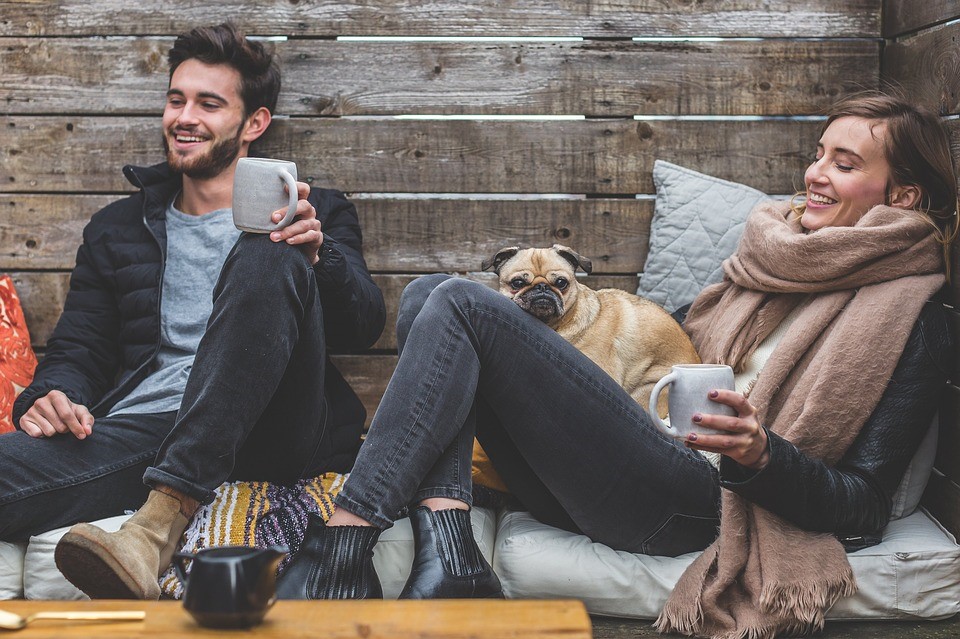 two white people and a dog lounging with coffee