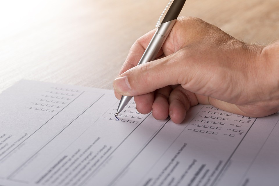 a person checking boxes in a paper survey with a pen