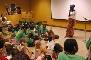 an woman speaking to a group of children in a room