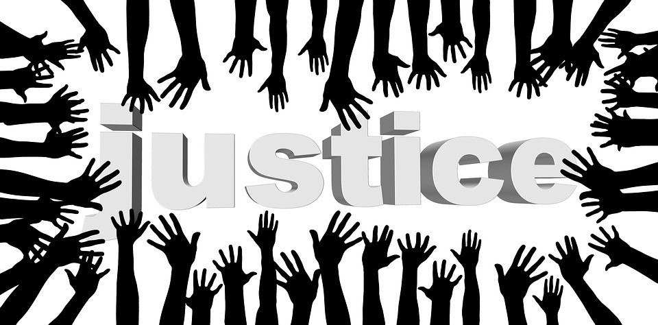 drawn black arms reaching towards the word justice written in grey text on a white background