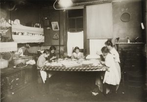 Image showing a group of children sitting around a table engaged in manual work, highlighting the harsh conditions often associated with child labor.