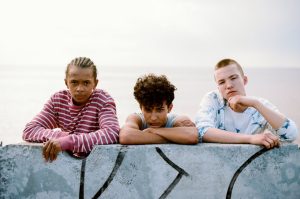 Three adolescents leaning forward on a wall ledge