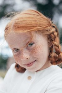 Close-up of a child with red hair looking at the camera and smiling