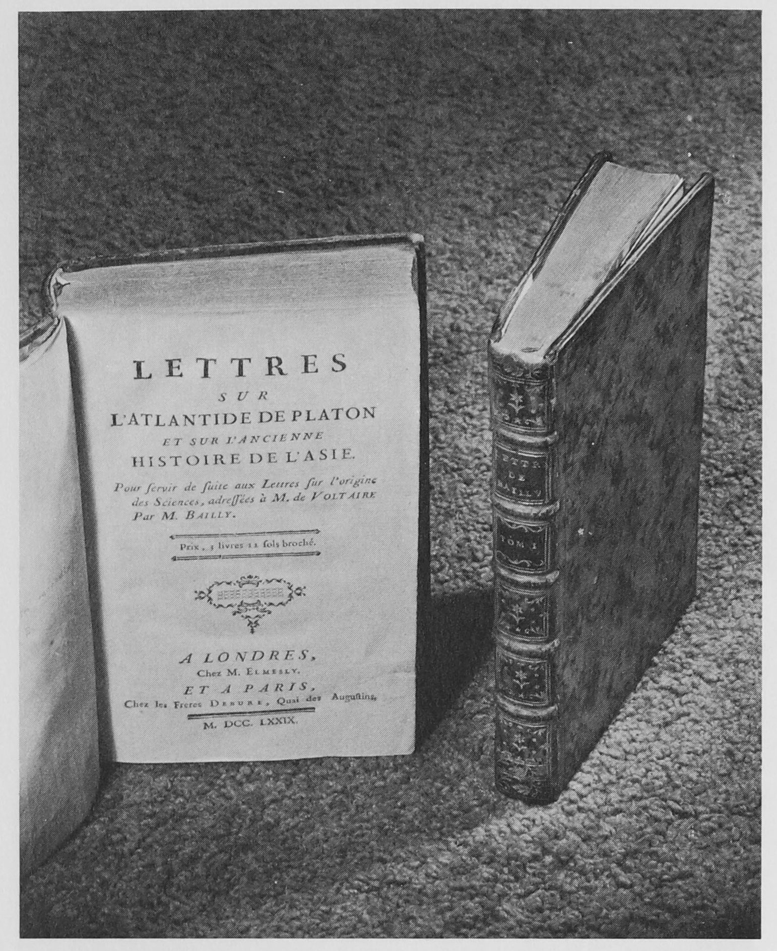 Two books standing on their ends. One is open to its title page: Lettres sur L'Atlantide De Platon et sur lancienne Histoire de L'ast.