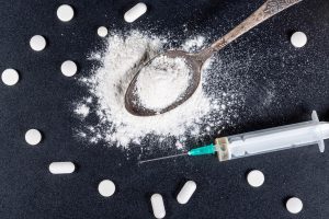 drug syringe, pills and heroin on spoon