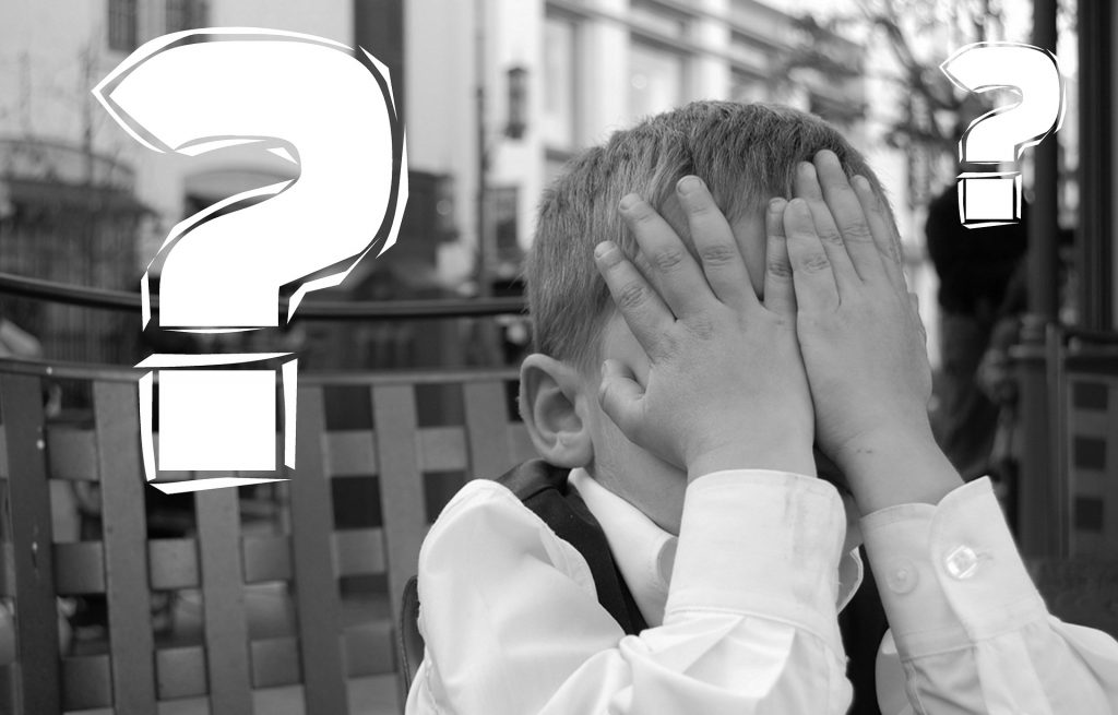 boy covering face with question marks