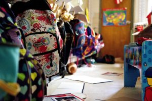 Backpacks are hung in a classroom.