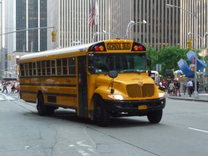A yellow school bus drives down a city street.