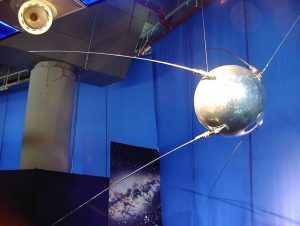 Image of Sputnik in a museum; round silver ball with leg-like antennae
