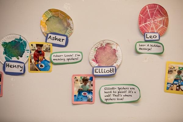 The image is of a wall with children's art mounted to it. Each piece of art is labeled with the child's name and the child's verbal statement about the art written out.
