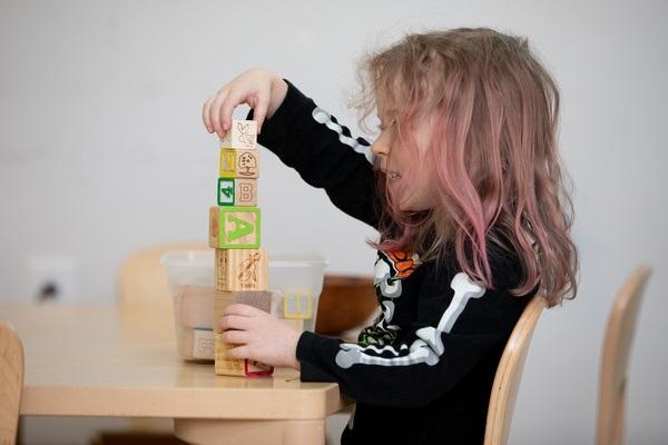 A child sits at a table stacking blocks.