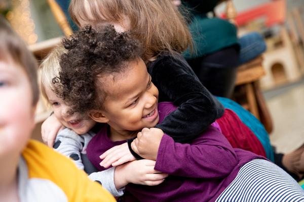 Three children hug each other in the classroom.