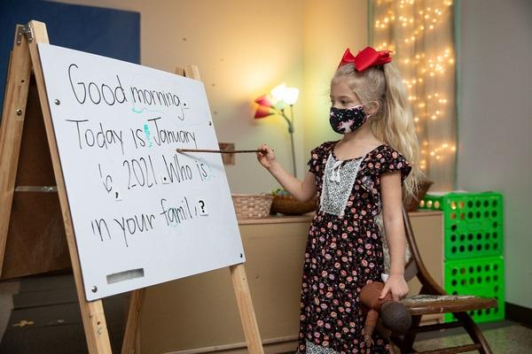 A child points to each word of the morning message on the board.