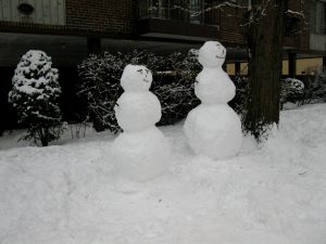 Two snowpeople are shown, each constructed of three round balls of snow