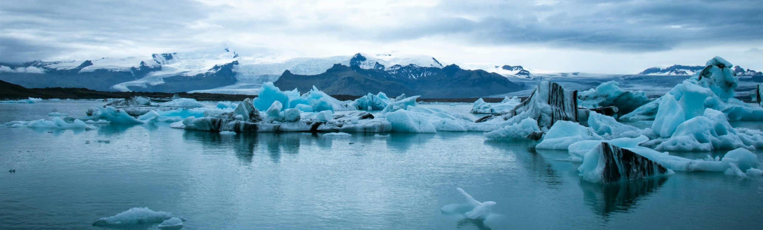 Scenic View Of Snow Capped Mountains, melting ice in lake, Under Cloudy Sky