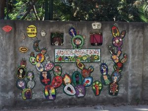 Wall mural with art symbols for inclusivity and the letters "Justicia Para Todos"